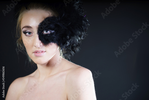 Studio shot of young woman with black feather half mask. photo