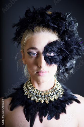 Studio shot of young woman with black feather half mask. photo