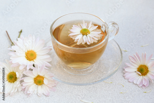 Glass cup of delicious chamomile tea on white table