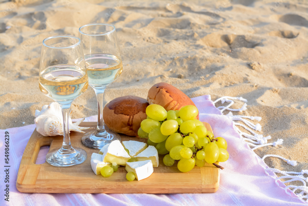 Fototapeta premium Glasses with white wine and snacks for beach picnic on sand outdoors