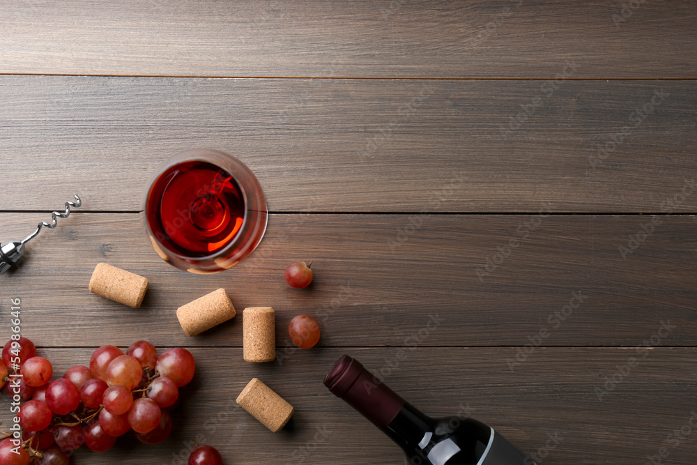 Wine, corks, grapes and corkscrew on wooden table, flat lay. Space for text