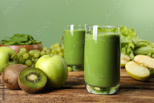 Green smoothie and fresh ingredients on wooden table. Space for text