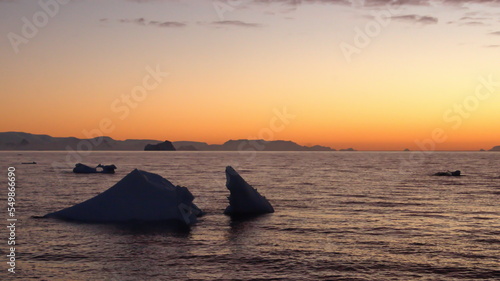 Sunset silhouetting icebergs floating in the Southern Ocean, at Cierva Cove, Antarctica