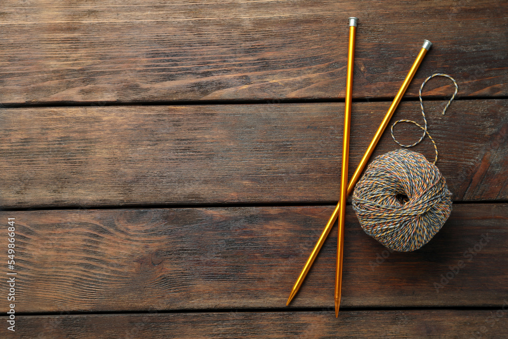 Soft woolen yarn and knitting needles on wooden table, flat lay. Space for text Soft woolen yarn and knitting needles on wooden table, flat lay. Space for text