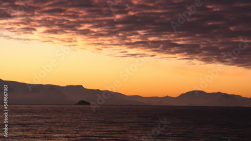 Popcorn clouds illuminated pink over the silhouette of a mountain  at sunset at Cierva Cove  Antarctica