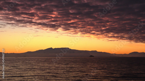 Popcorn clouds illuminated pink over the silhouette of a mountain  at sunset at Cierva Cove  Antarctica