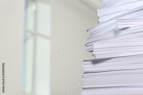 Stack of paper sheets against blurred background  closeup. Space for text