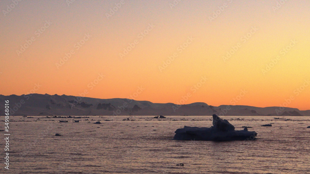 Sunset silhouetting icebergs floating in the Southern Ocean, at Cierva Cove, Antarctica