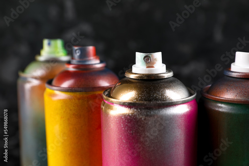 Used cans of spray paint on black marble background, closeup