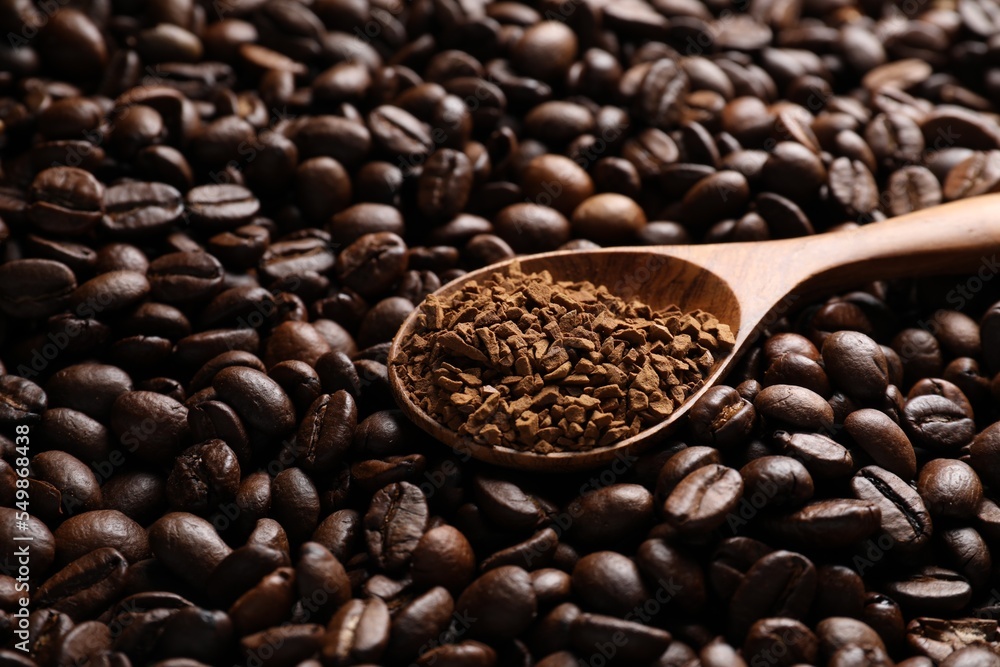 Fototapeta premium Spoon with instant coffee on roasted beans, closeup. Space for text