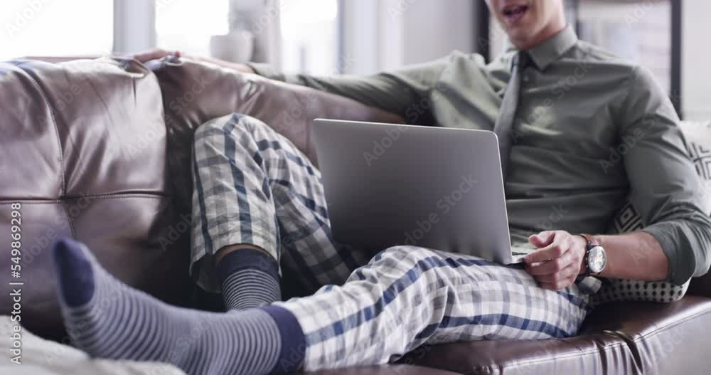 Video call, laptop and remote work with a business man on the sofa in the living room of his home. Meeting, virtual and pjyamas with a male employee working from his house with fast food takeaway Video call, laptop and remote work with a business man on the sofa in the living room of his home. Meeting, virtual and pjyamas with a male employee working from his house with fast food takeaway