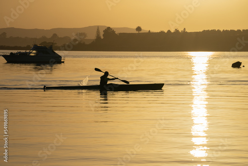 Downtown waterfront sunrise as paddler in silhouette floats past