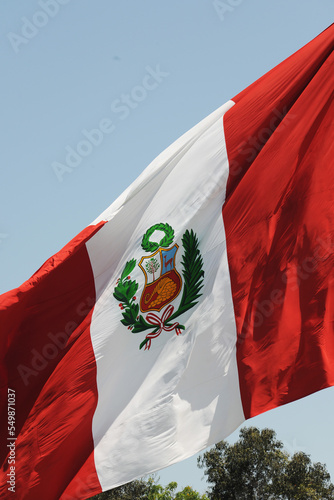 Peru national flag cloth fabric waving on beautiful sky.
