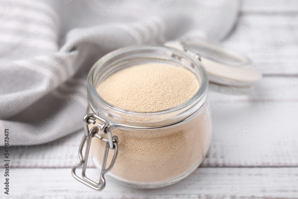 Granulated yeast in glass jar on white wooden table, closeup Granulated yeast in glass jar on white wooden table, closeup