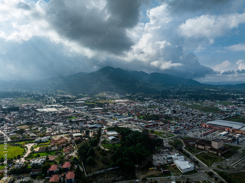 Aerial view of a large mountain at sunset with sun rays breaking through the clouds. The beautiful city 
 San Cristóbal de Las Casas in Mexico.