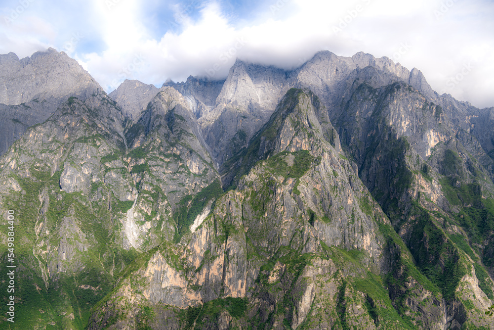 Beautiful panorama view of Jade Dragon snow mountain from hiking trail path of Tiger Leaping Gorge with blue sky in background, is located in Yulong Naxi autonomous in Lijiang city, Yunnan, China