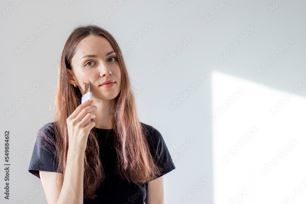 Young woman cleanses her facial pores with an ultrasonic scrubber. Self-care at home. Girl wants clear skin Young woman cleanses her facial pores with an ultrasonic scrubber. Self-care at home. Girl wants clear skin