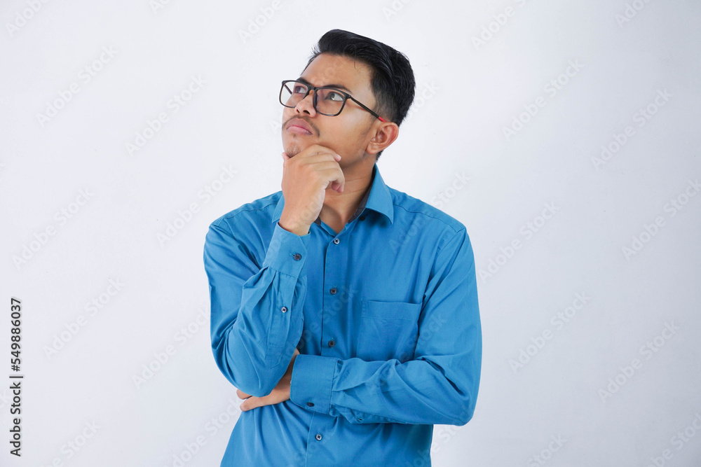 young handsome asian man with glasses thinking and looking for ideas while holding the chin wearing blue shirt isolated on white background young handsome asian man with glasses thinking and looking for ideas while holding the chin wearing blue shirt isolated on white background
