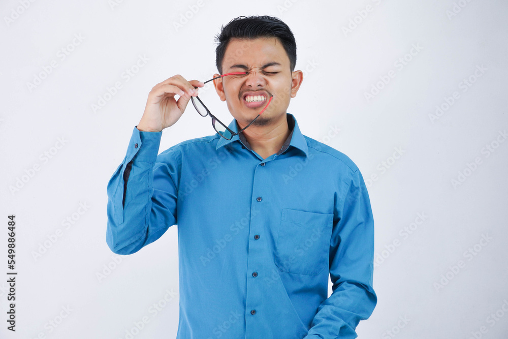 funny face young asian man got poked in the eye with a glasses wearing blue shirt isolated on white background funny face young asian man got poked in the eye with a glasses wearing blue shirt isolated on white background