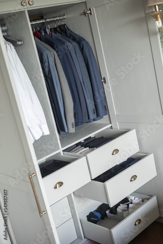 Minimalist male wardrobe neatly folded and hanging clothes dresser drawer vertical storage organizer © kostikovanata