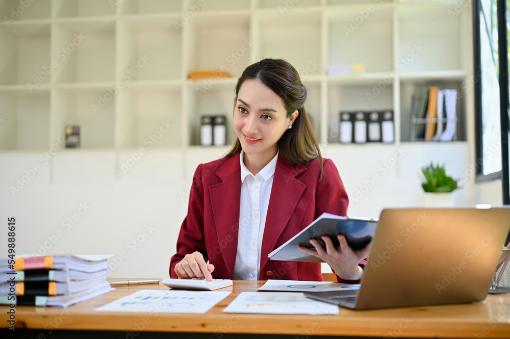 Charming Asian businesswoman or accountant woking at her office desk, using calculator Charming Asian businesswoman or accountant woking at her office desk, using calculator