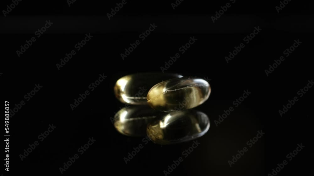 Omega 3 Gold oil capsules on black background, rotation. Close-up of rotating golden pills.Vitamins supplements pills omega 3. Cod liver oil medicines. Fish oil capsules.Omega 3 Fish oil vitamin gel Omega 3 Gold oil capsules on black background, rotation. Close-up of rotating golden pills.Vitamins supplements pills omega 3. Cod liver oil medicines. Fish oil capsules.Omega 3 Fish oil vitamin gel