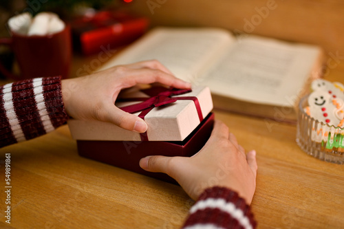 close-up image, A female opening a surprise gift box at her desk. Holiday presents or gift