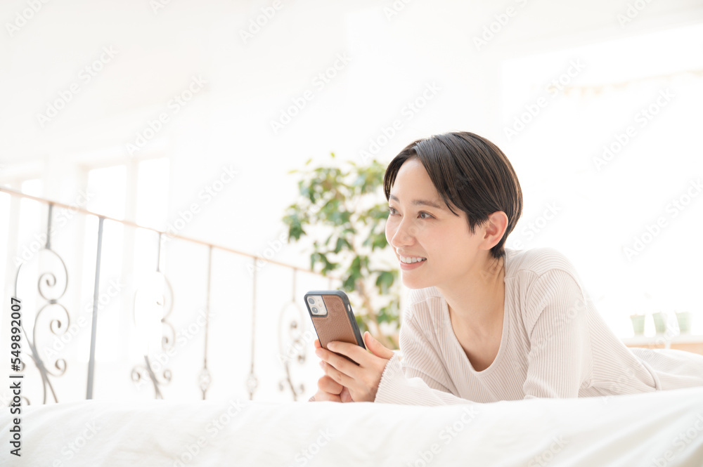 Beautiful Asian woman lying down and holding a phone Beautiful Asian woman lying down and holding a phone