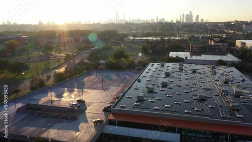 Aerial dolly in over industrial buildings with solar panels at sunrise, with New York cityscape in the distance (ID: 549895435)