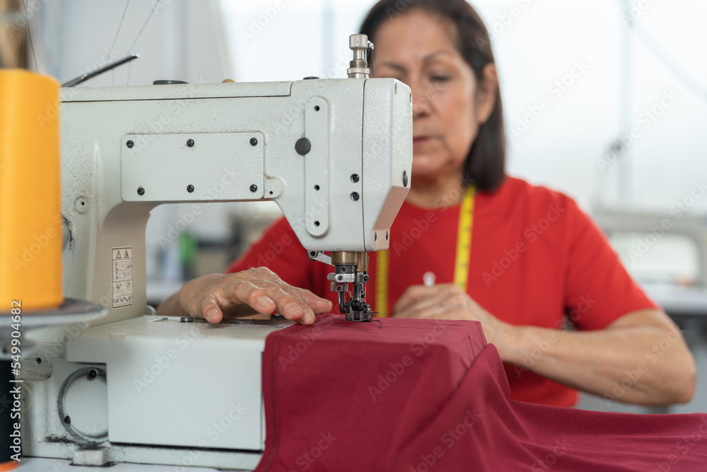 Focus on a sewing machine in a workshop while a woman is working