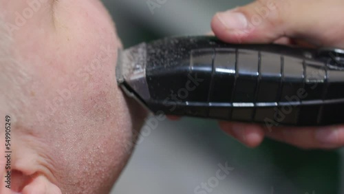 Close-up view of a barber shaving face with electric razor. Detailed shot of a man having a daily care routine procedure. High quality 4k footage photo