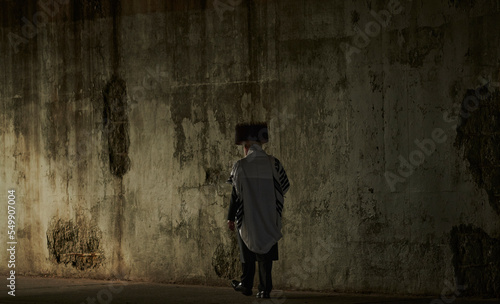 a hasidic jewish man walking down the street under the bridge in williamsburg brooklyn