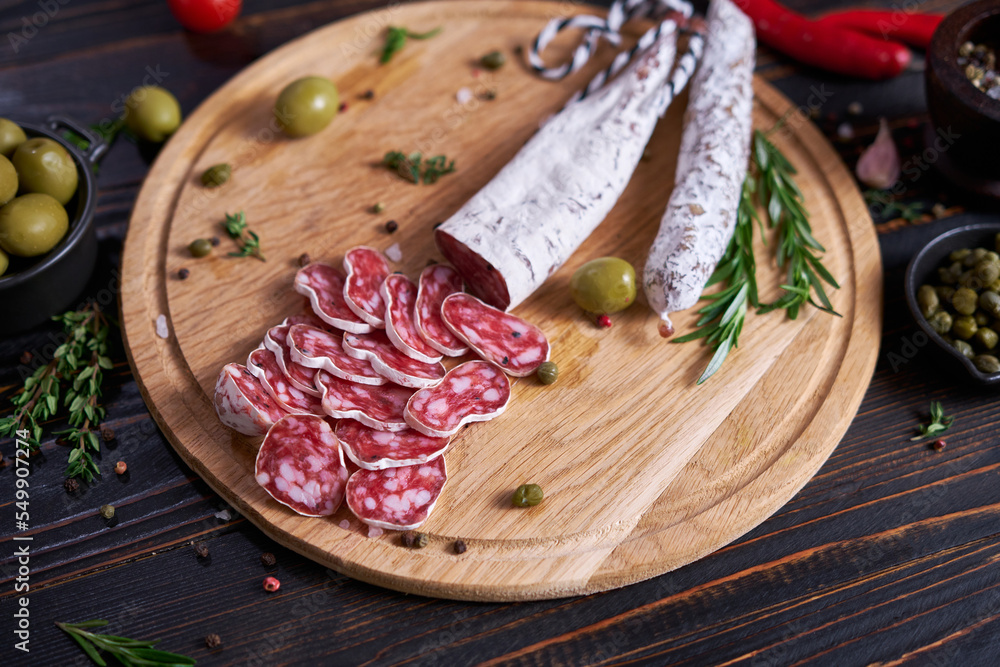 Spanish fuet salami sausageon wooden cutting board at domestic kitchen Spanish fuet salami sausageon wooden cutting board at domestic kitchen