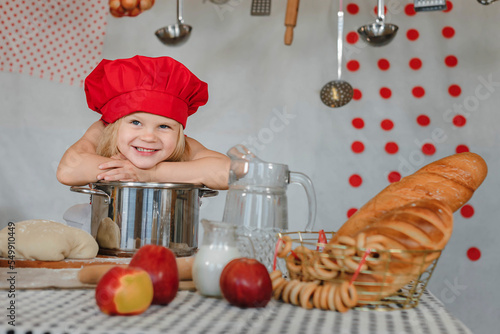 little girl in the kitchen in a red chef's hat