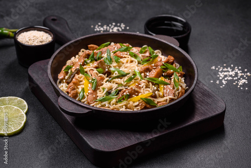 Tasty dish of Asian cuisine with rice noodles, chicken, asparagus, pepper, sesame seeds and soy sauce