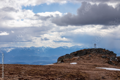 Scenic view on summit cross of mountain peak Grosser Sauofen  Saualpe  Lavanttal Alps  Carinthia  Austria  Europe. Hiking trail in Wolfsberg on cloudy day. View on Karawanks  Karawanken  mountains