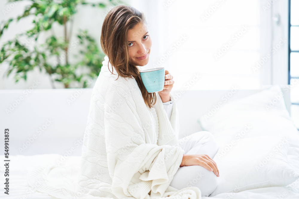 Young nice woman in bed with coffee or tea mug