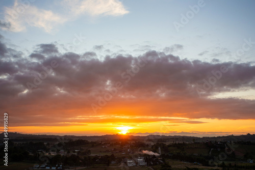 Morning view at morning sunrise, clouds in orange crimson colors. Silhouettes of houses roofs, trees, and a monastery on the hill. Colorful scenery skyline background.