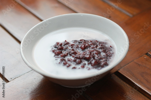 a bowl of black sticky rice porridge with coconut milk