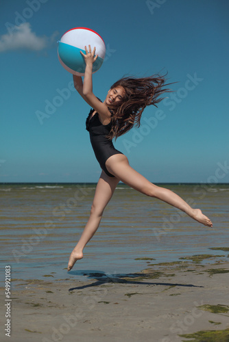 young graceful and flexible gymnast in swimsuit by the sea