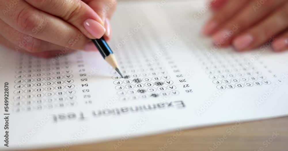 Hand with pencil on examination paper chooses answer to question Hand with pencil on examination paper chooses answer to question