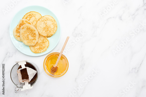 For breakfast, pancake, honey and coffee in a drip pack. Place for text. Copy space. Marble background. Top view. Flat lay.