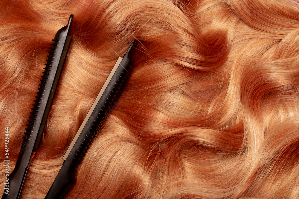 Naklejka premium Iron for straightening and styling hair in a beauty salon. Curling your hair into beautiful wavy curls with a hair straightener. Flat lay top view as background with place for text.