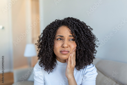 Tableau sur toile Portrait of unhappy African-American woman suffering from toothache at home