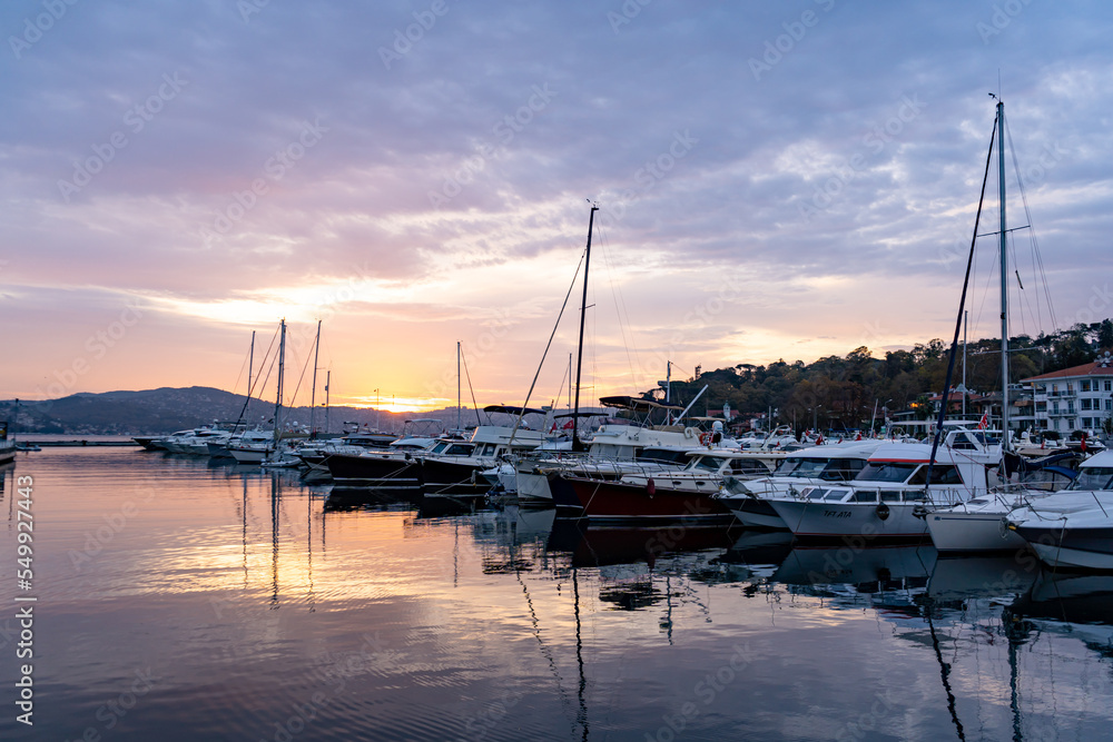 Sailboats at Tarabya yacht marina in Istanbul. Reflection of yachts and hotel. Blue sky and natural white clouds. Sailboats at Tarabya yacht marina in Istanbul. Reflection of yachts and hotel. Blue sky and natural white clouds.
