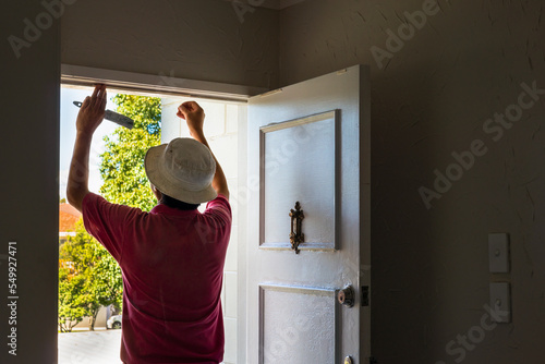 Man applying draught stopping foam tape to the door frame. Home maintenance to meet the healthy home standard. Auckland. photo