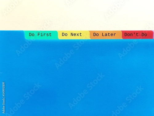 Document folder on copy space blue background with tag DO FIRST DO NEXT DO LATER DON'T DO, concept of time management skills, knowing priority of tasks, difference between important and urgent tasks