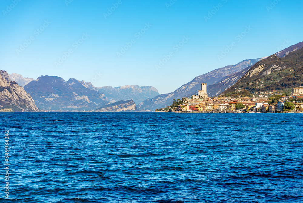 Lake Garda (Lago di Garda) and the small Malcesine village with the castle. Verona province, Italy, Veneto, southern Europe. On background the coast of the Lombardy and Trentino-Alto Adige.