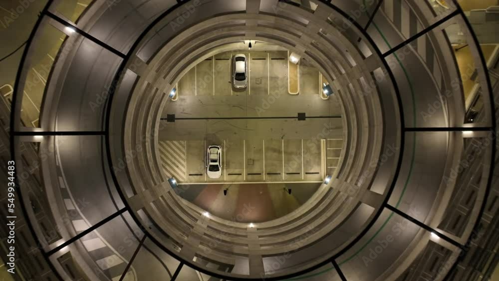 Drone shot of multi story car park at night time. Symmetrical top down view. Flying upwards. Drone shot of multi story car park at night time. Symmetrical top down view. Flying upwards.