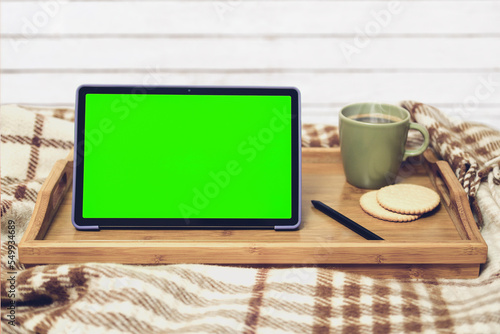 Fototapeta Naklejka Na Ścianę i Meble -  Digital tablet with green screen and stylus pencil, a cup of coffee. Work at home concept. Wooden background.